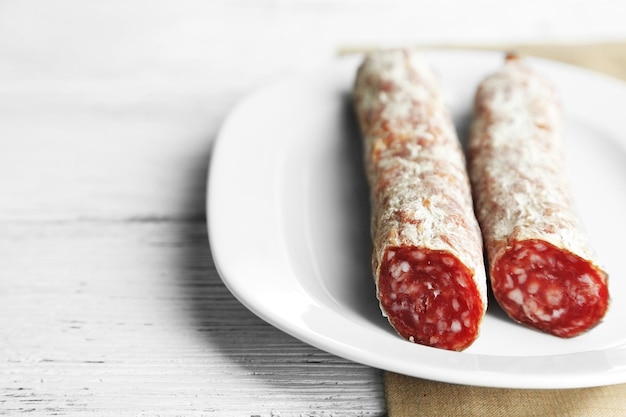 Italian salami on plate on wooden background