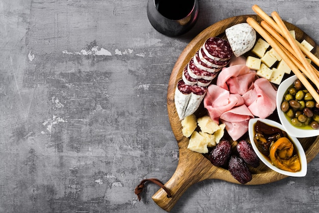 Foto spuntino italiano e antipasti su un vassoio e vino rosso prosciutto salame pomodori olive formaggio