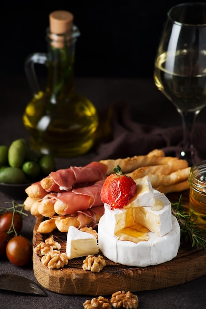 Italian snack set - brie cheese, camembert, grissini, jamon, wine, nuts, honey. Snacks for wine