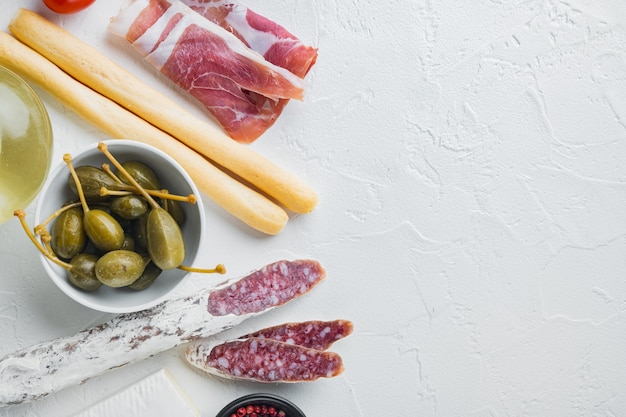 Spuntini italiani, formaggio a base di carne, set di erbe, su sfondo bianco, vista dall'alto con copia spazio per il testo