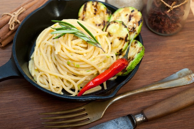 Italian spaghetti pasta with zucchini sauce on iron skillet