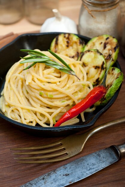 Italian spaghetti pasta with zucchini sauce on iron skillet