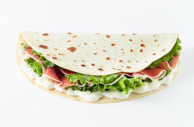 Italian street food flat lay with piadina isolated on a white background Piadina romagnola Italian flatbread with prosciutto salad and cream cheese