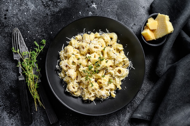 Italian Tortellini pasta with Parmesan cheese. Black background. Top view