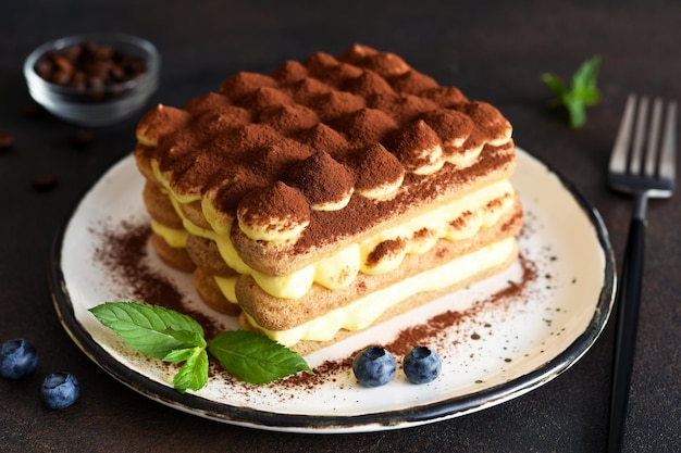 Dessert tiramisù tradizionale italiano in un piatto su fondo di cemento