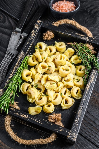 Pasta italiana tradizionale dei tortellini con gli spinaci in un vassoio di legno sulla tavola di legno. vista dall'alto.