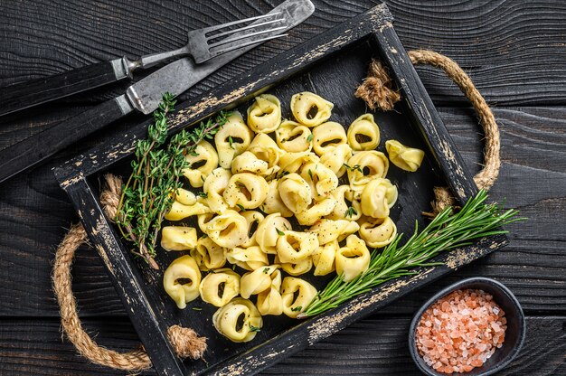 Italian traditional tortellini pasta with spinach in a wooden tray