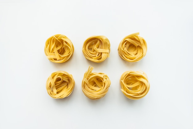 Italian wheat pasta tagliatelle isolated on white background. Top view