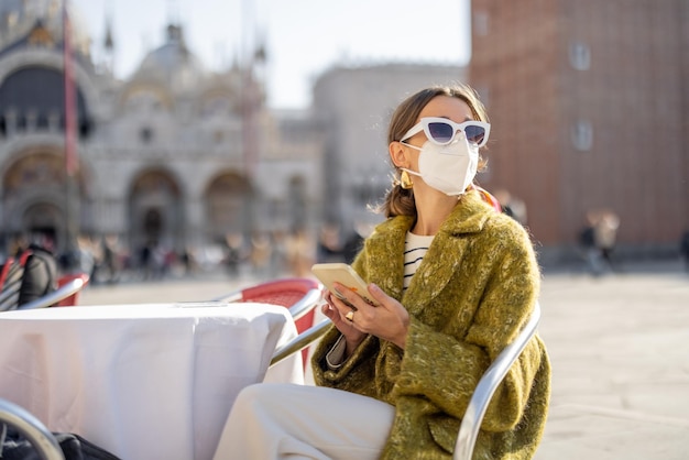 Italian woman in medical mask at cafe in the center of venice