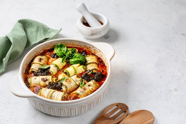 Italian zucchini rolls with cream cheese filling baked in tomato sauce on a white background