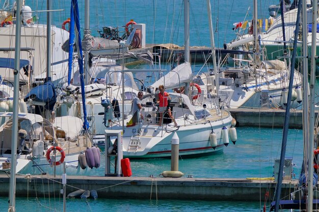 Foto italië, sicilië, middellandse zee, marina di ragusa (provincie ragusa); 17 juni 2023, echtpaar op een zeilboot in de haven - editorial