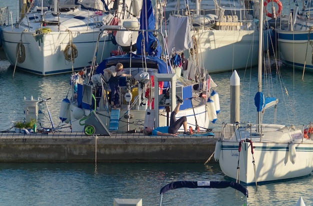Italië, Sicilië, Middellandse Zee, Marina di Ragusa (provincie Ragusa); 30 oktober 2020, mensen en zeilboten in de haven - REDACTIE