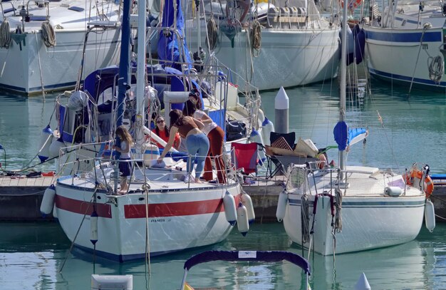 Italië, Sicilië, Middellandse Zee, Marina di Ragusa (provincie Ragusa); 6 februari 2021, mensen op een zeilboot in de haven - REDACTIE