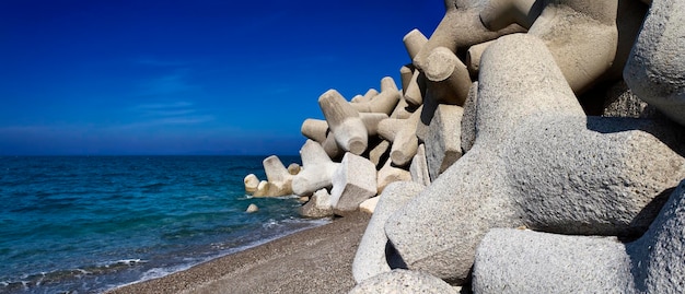 Italië, Sicilië, provincie Messina, betonnen tetrapoden op het strand bij een haven in aanbouw