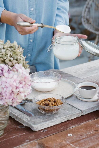 Italië, vrouw die ontbijt klaarmaakt met muesli op terras, gedeeltelijk uitzicht