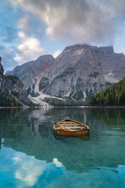 イタリア。ドロミテの山々とブラス湖のボート、秋の風景、垂直。