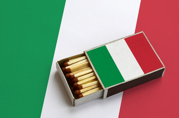 Italy flag  is shown in an open matchbox, which is filled with matches and lies on a large flag