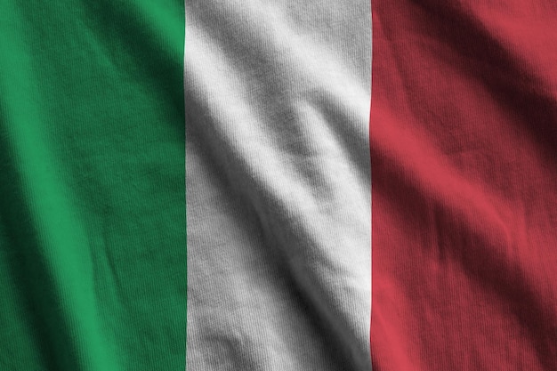 Italy flag with big folds waving close up under the studio light indoors The official symbols and colors in banner