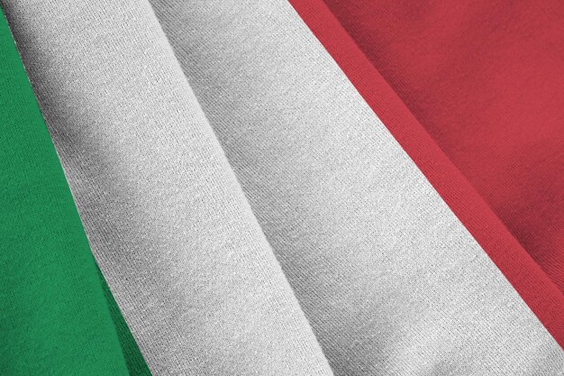 Italy flag with big folds waving close up under the studio light indoors the official symbols and colors in banner