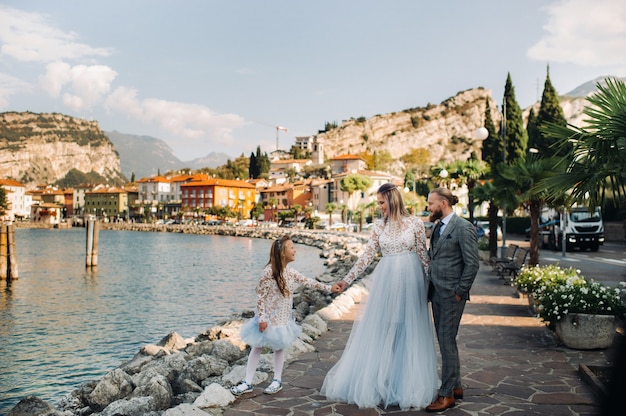 Italy, Lake Garda. Beautiful family on the shores of lake Garda in Italy at the foot of the Alps. Father, mother and daughter in Italy.