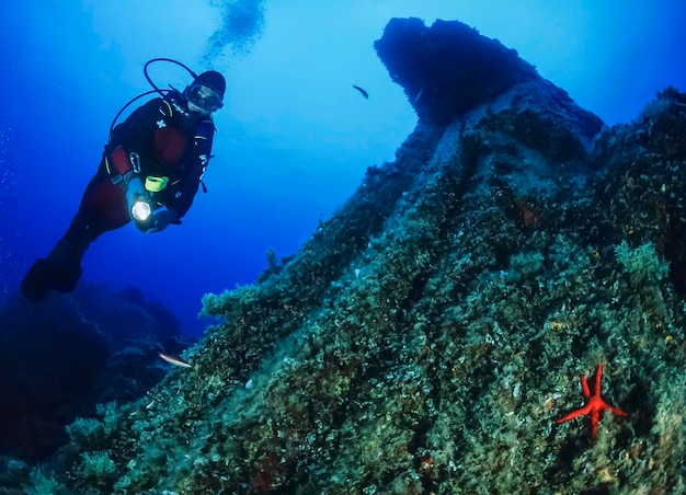Italy, ponza island, tyrrhenian sea, u.w. photo, scuba diver and starfish (film scan)