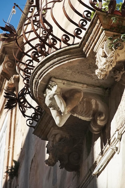 Italy, Sicily, Ragusa Ibla, original statue under a balcony in a baroque palace