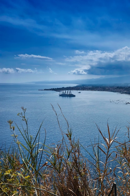 이탈리아 시칠리아 타오르미나(Italy Sicily Taormina)는 유람선이 있는 동부 시칠리아 해안선과 지아르디니 낙속스 베이(Giardini Naxox bay)의 전망을 제공합니다.