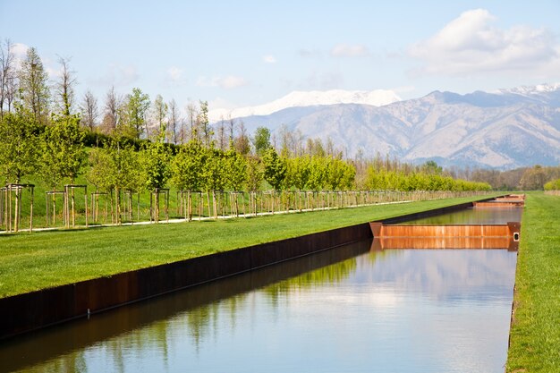 Italy - Water pool in green field with Alps mountains on background