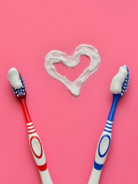 items for oral hygiene and toothpaste heart on a pink background close up