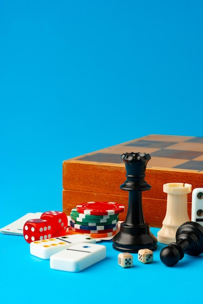 Items for playing chess poker and domino on blue background studio shot