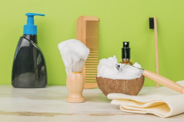 Items voor scheren, wassen en kammen op een houten tafel op een groene achtergrond.