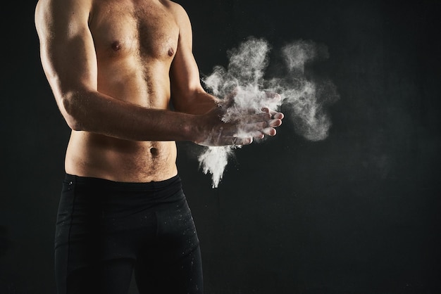 Its all about the grip Shot of a mans torso while applying talc powder to his hands against a dark background