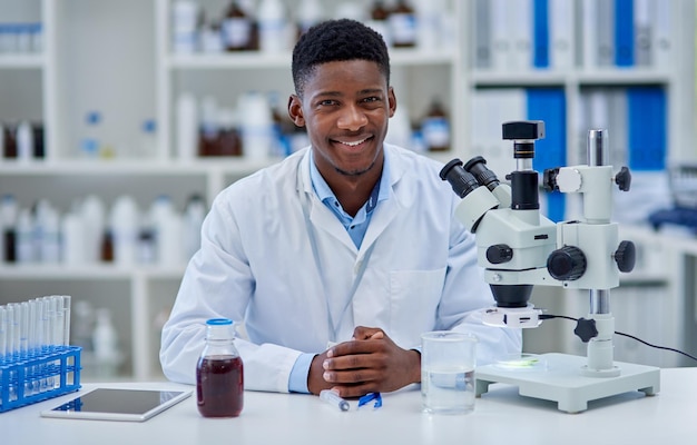 Это был долгий продуктивный день Портрет веселого молодого ученого-мужчины, стоящего за своим столом в лаборатории в течение дня