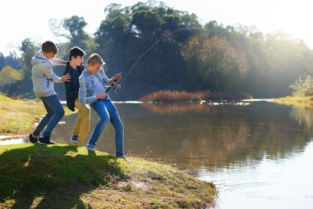 湖で釣りをしている少年たちのグループの大きなワンショット