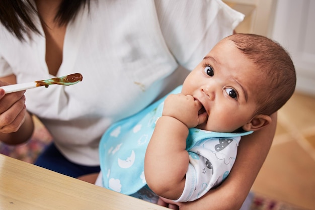 その指をなめる彼女の愛らしい男の子に餌をやる母親の良いショット