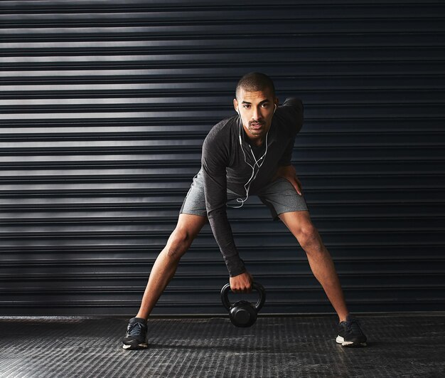 Its not going to lift itself Shot of an athletic young man working out with a kettlebell in the gym