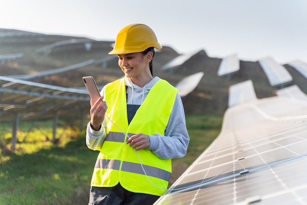 Its great female engineer feeling happy while charging mobile\
phone from solar panels she working on maintenance of contemporary\
photovoltaic panels on solar power station