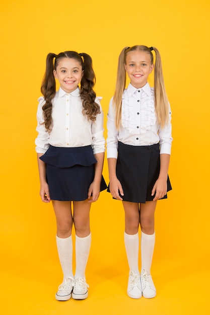 Its important to have friends. Happy small friends. Little school friends smiling on yellow background. Adorable girl friends enjoying their friendship.