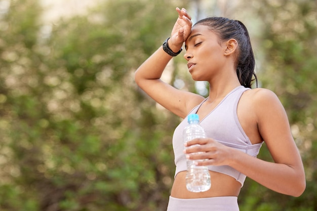 Its possibly too hot to be out. Shot of a sporty young woman having looking tired while drinking water outdoors.