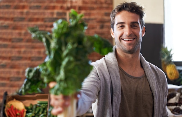 Its rich in iron Portrait of a young man in a grocery store holding up spinach to the camera