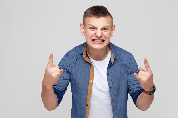 Its rock n roll baby funny young man looking at camera with rock sing and open mouth