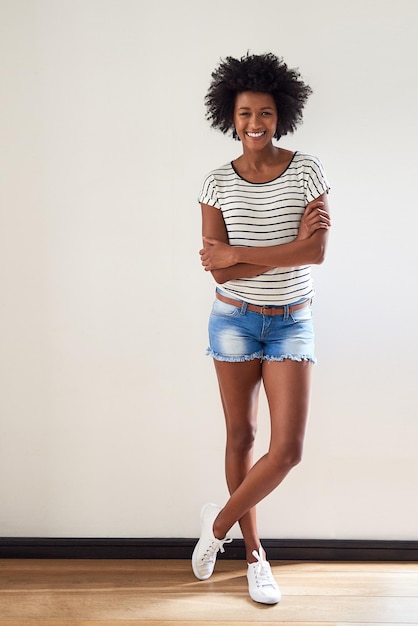 Its shorts season again Portrait of an attractive and happy young woman wearing a striped sweater and denim shorts indoors