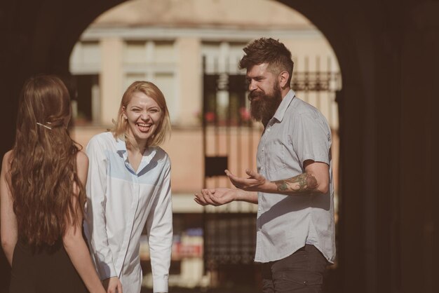 Foto È così divertente l'amicizia inizia con un sorriso uomo barbuto e belle donne che sorridono per strada fidanzato che esce con fidanzate persone che si godono la reciproca compagnia legami di amicizia amici felici