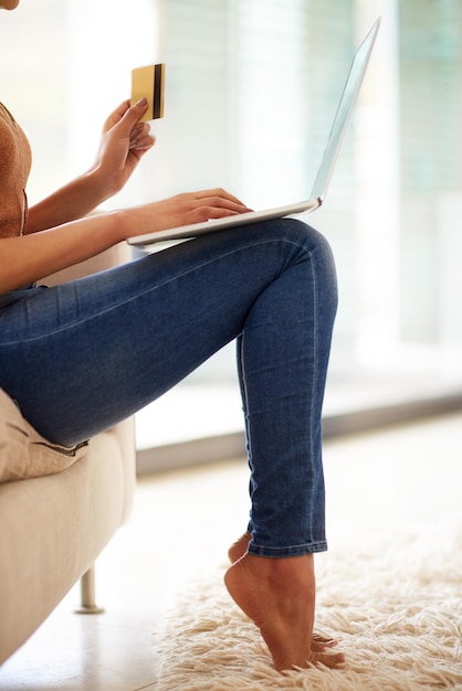 Its so lovely to shop online barefoot on the sofa Shot of an unrecognizable woman using a laptop and credit card at home