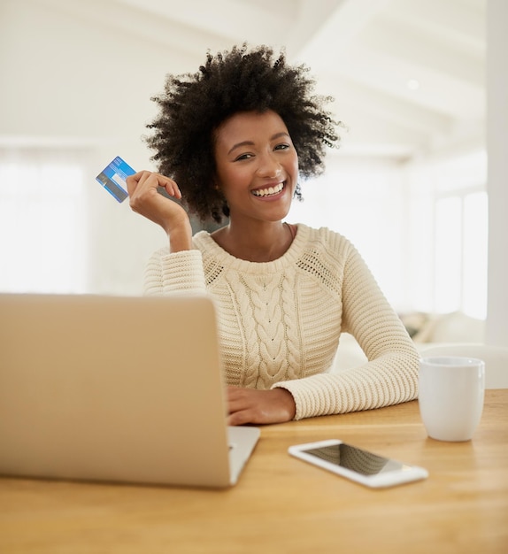 Its time to spend some money Portrait of an attractive young woman shopping online using her laptop while sitting on the sofa at home