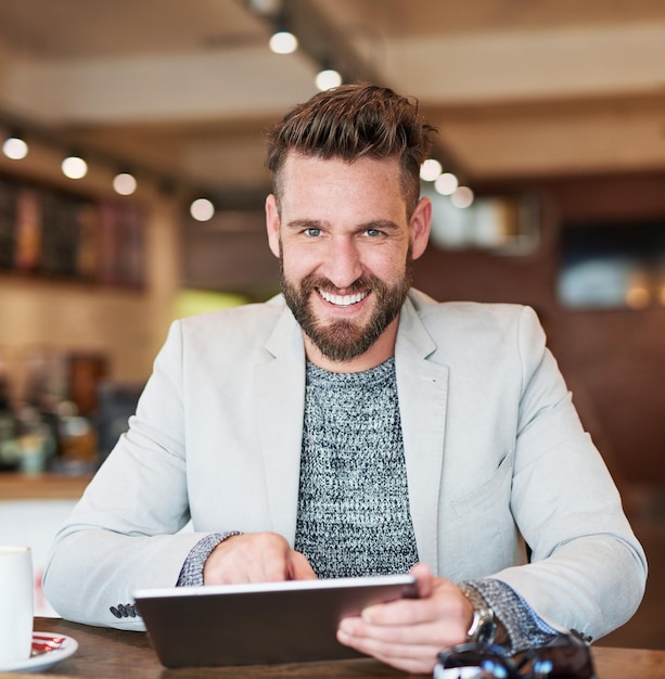 Its a tool for success Cropped portrait of a modern businessman using his digital tablet in a coffee shop