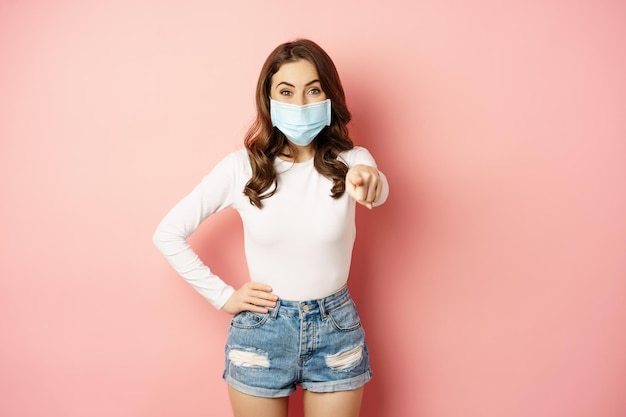 Its you happy smiling woman in medical face mask pointing finger at camera congratulating praising i...