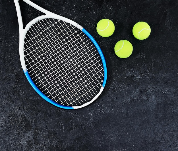 Фото Ваша очередь подавать. снимок одной теннисной ракетки и нескольких теннисных мячей на темном фоне внутри студии.