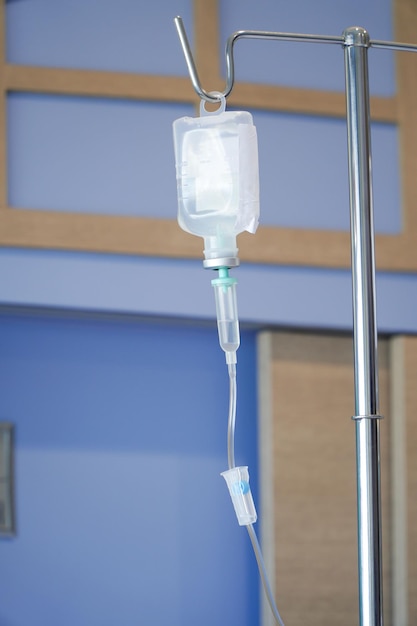 Iv drip chamber and iv bag of solution with patient on bed blurd background in patient room Hospital