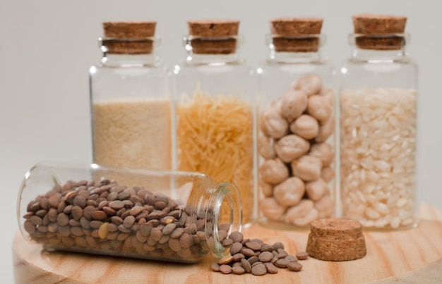 ive glass jars with cork stoppers, lentils, pasta and rice, soft greenish background